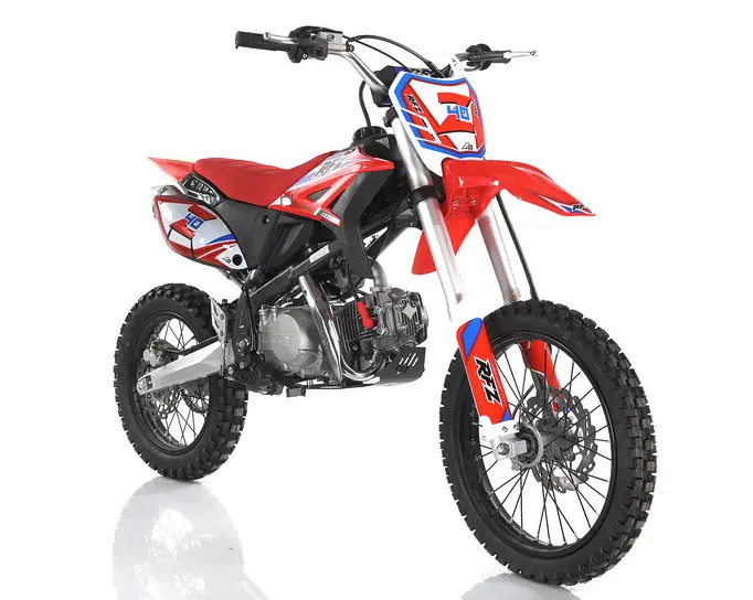 A red and white dirt bike is parked on the ground.