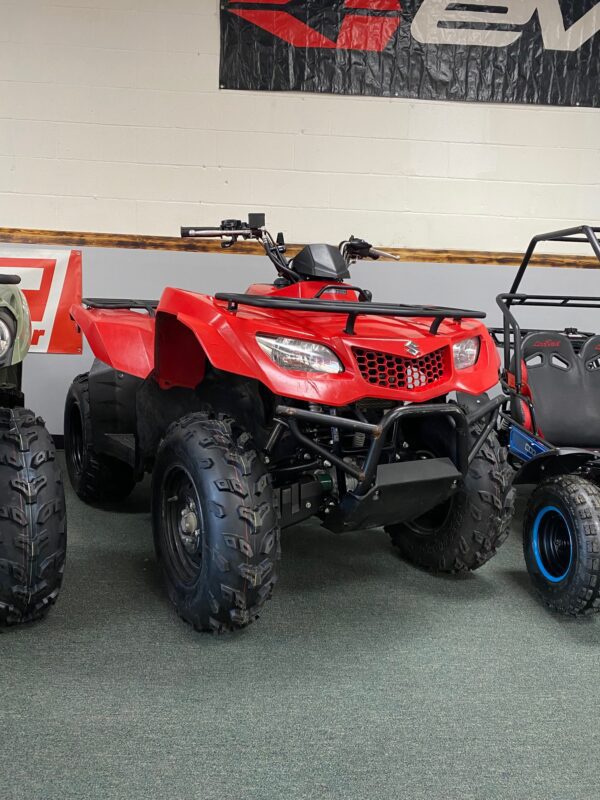 A red four wheeler parked next to another atv.