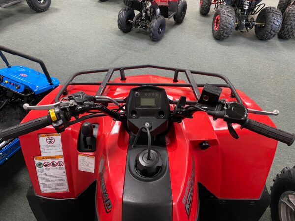 A red atv parked in a showroom with other vehicles.