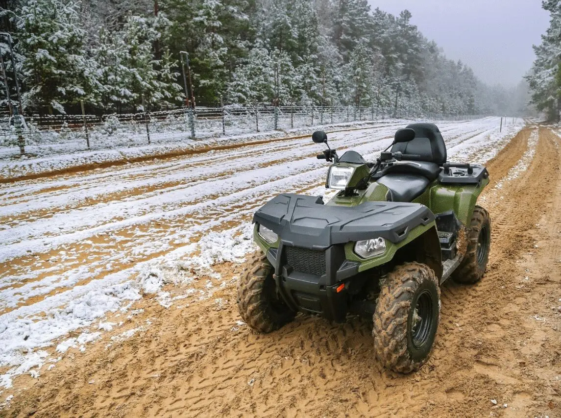 A green atv parked on the side of a dirt road.