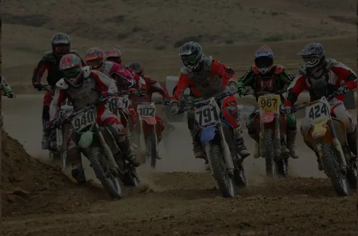 A group of people on motorcycles racing in the dirt.