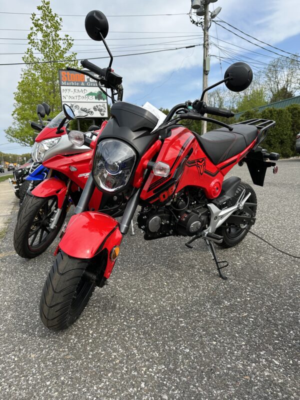 Two motorcycles parked in a parking lot on the side of the road.