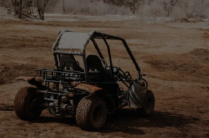 A small buggy is parked in the dirt.