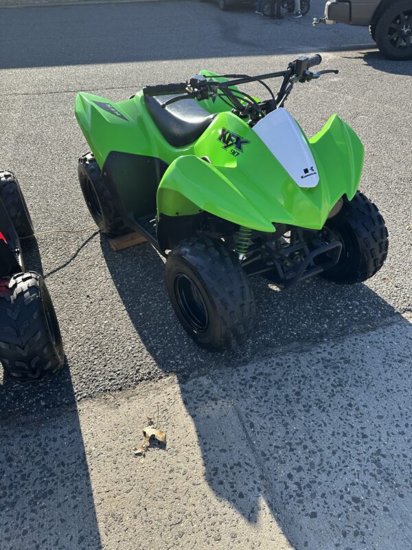 A green atv parked on the side of a road.