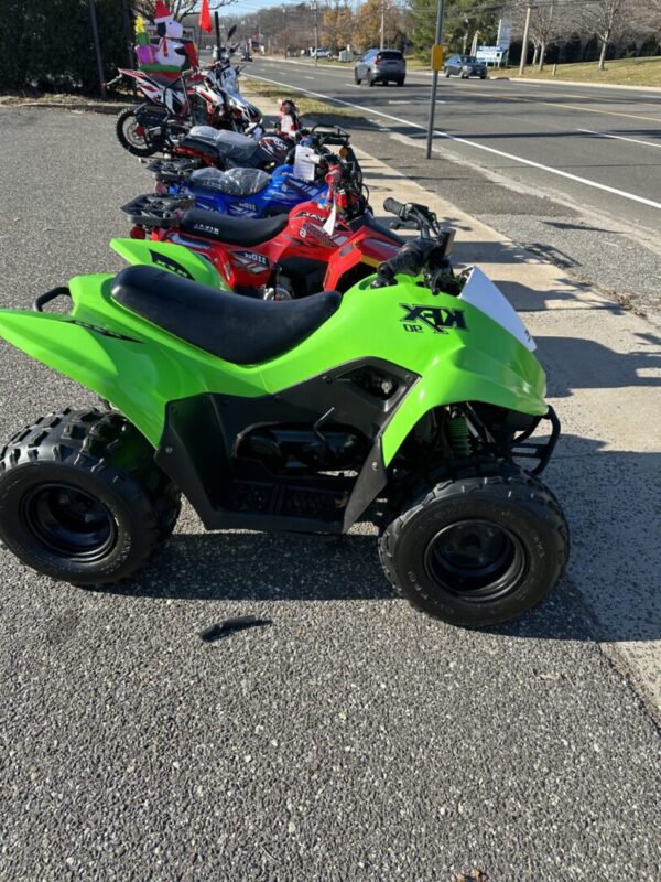 A group of four kids on atv 's parked in the street.