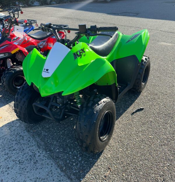 A green atv parked in the middle of a parking lot.